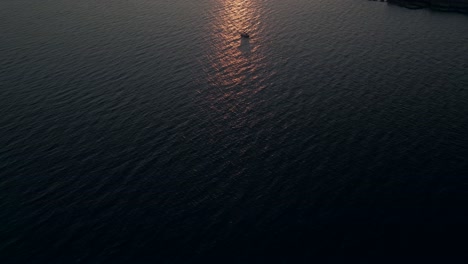 a sailboat sailing towards the open sea at dawn - aerial