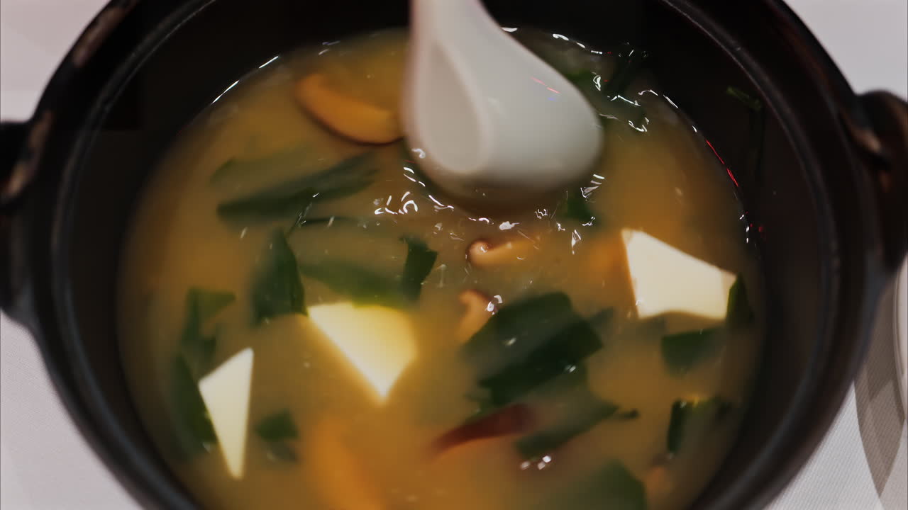 Close up of a woman mixing a miso soup at a restaurant