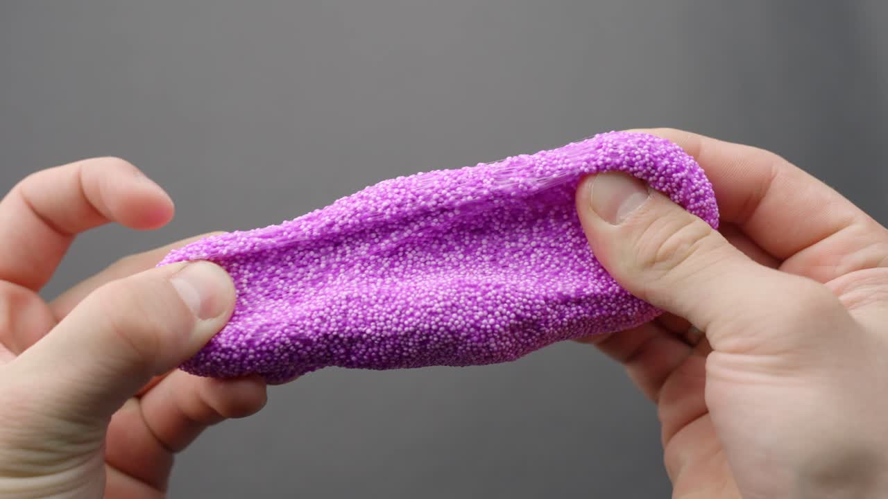 POV of hands stretching purple foam slime into thin strands showing texture