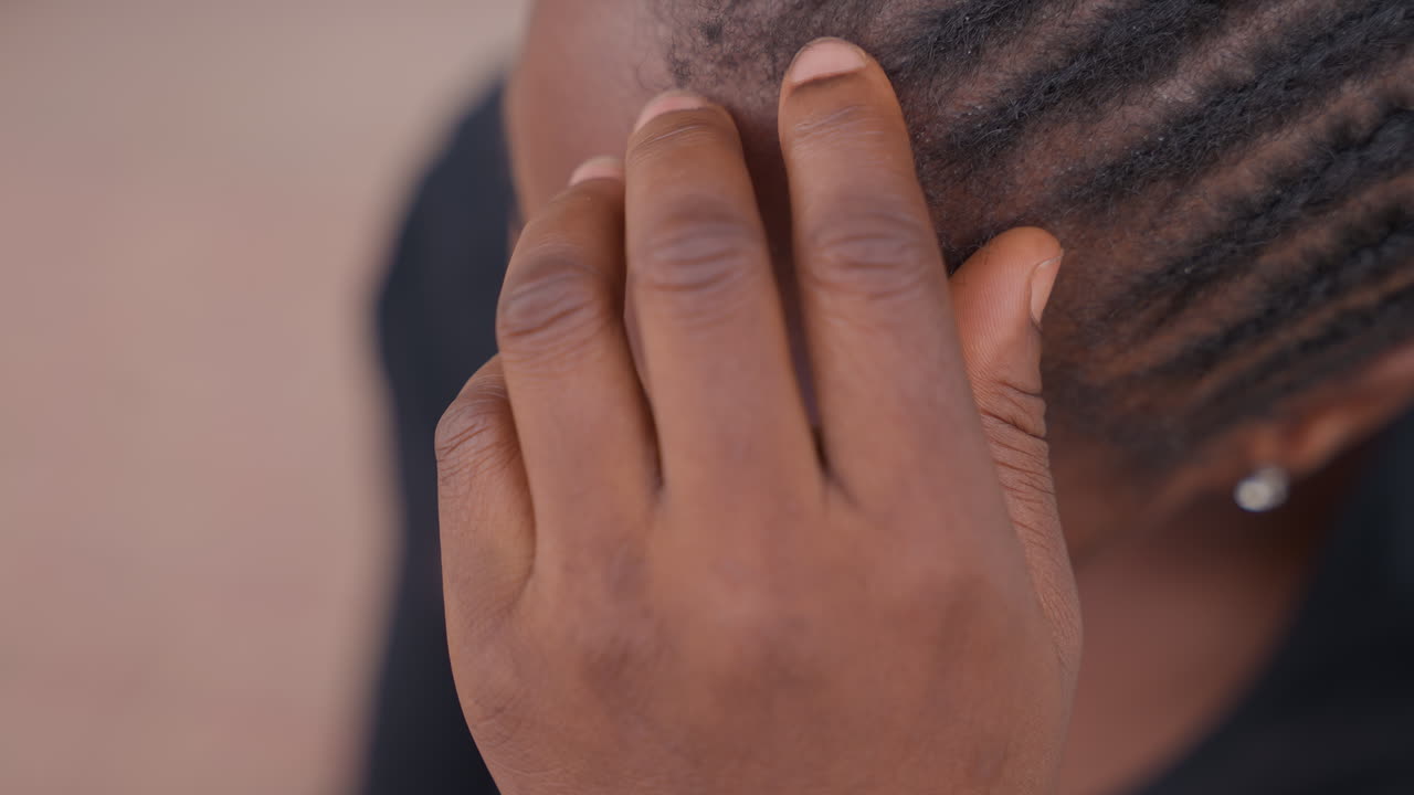 Black girl touching hairline and braids with fingers, calming preperformance ritual with focused hand movement, closeup of scalp and nails, subtle tension release, warm skin tones