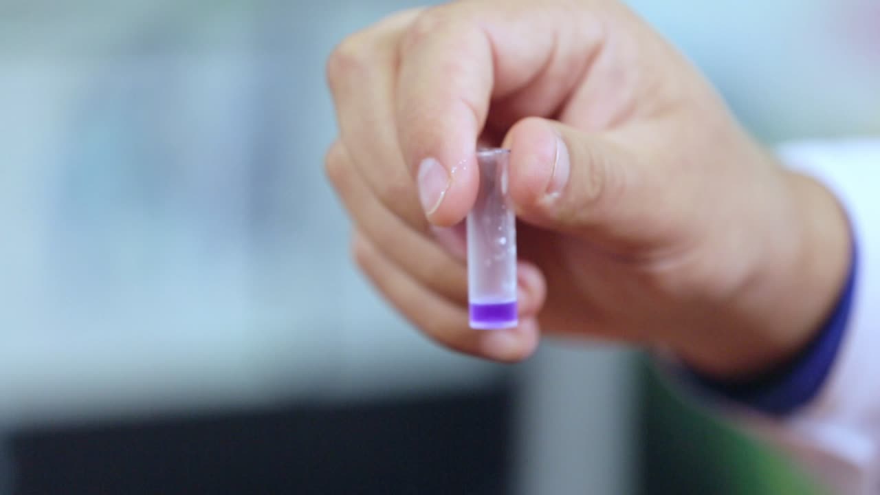 vial de laboratorio con líquido púrpura en la mano del científico. pruebas de laboratorio de ciencia