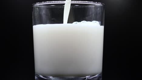 Gießen-Von-Milch-In-Ein-Transparentes-Glas,-Isoliert-Auf-Schwarzem-Hintergrund---Nahaufnahme
