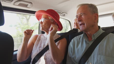 group of senior friends sitting in back of people carrier being driven to vacation