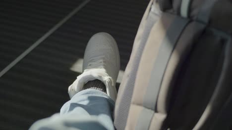 a person's foot resting on a seat inside a train, with a backpack nearby