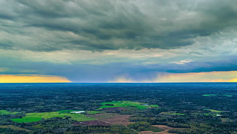 timelapse of rain clouds moving over the green forest and field.