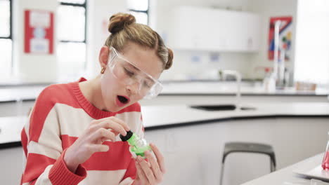 in school, girl wearing safety goggles conducting science experiment with focus