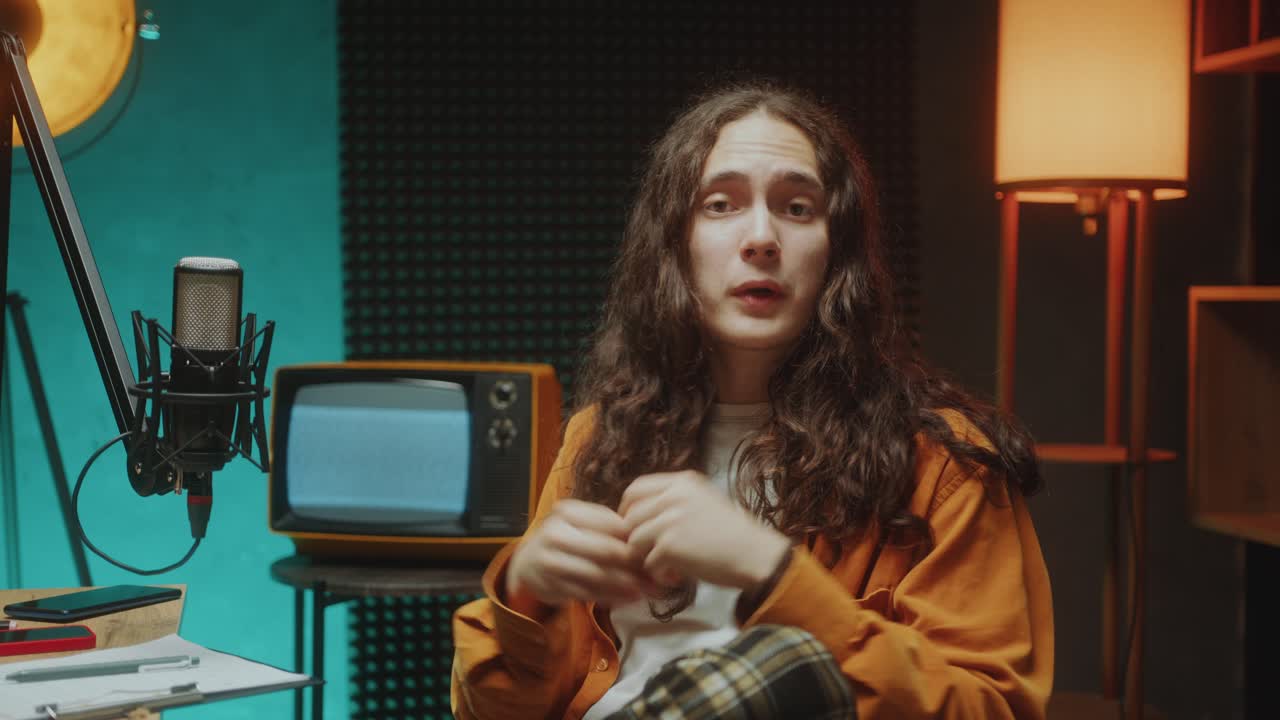 Young Blogger Talking in Mic and Looking at Camera in Podcast Recording Studio