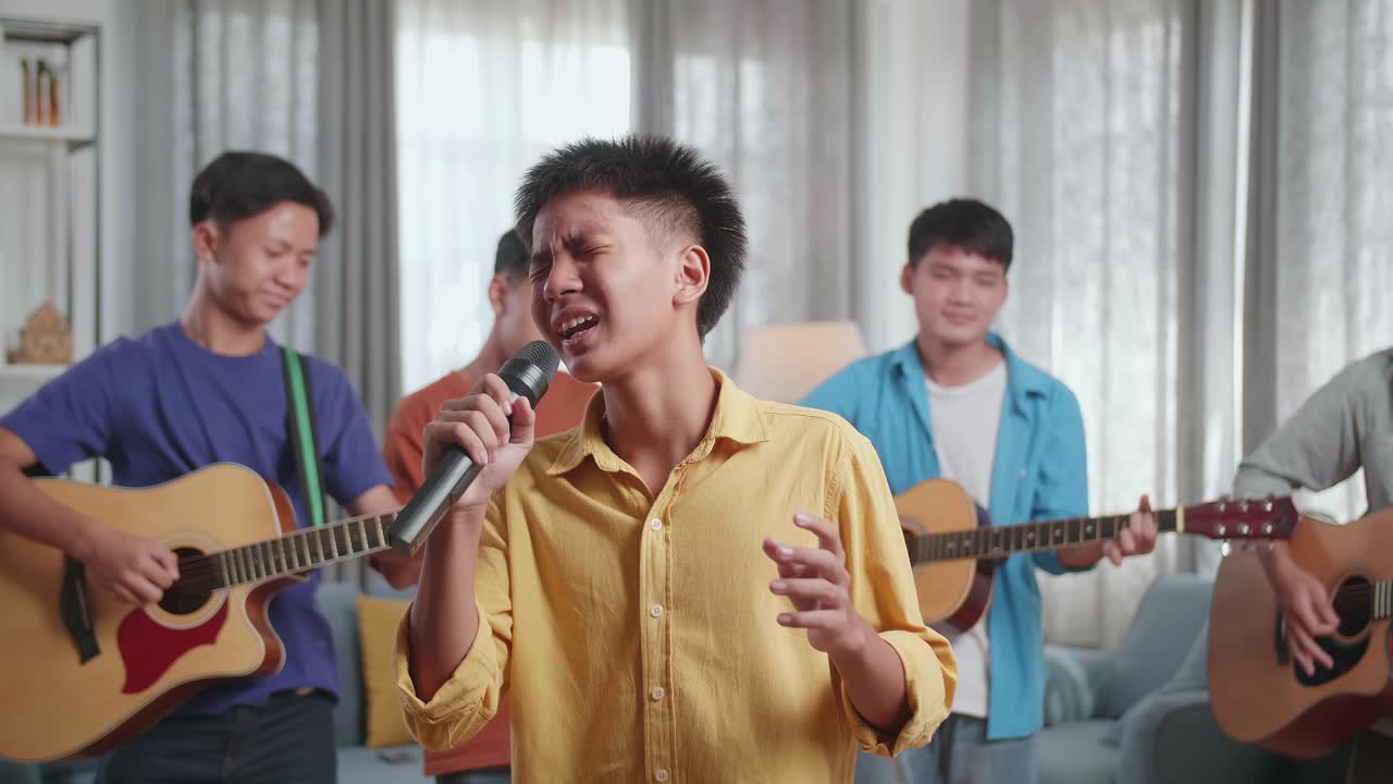 젊은 아시아 친구 들 의 그룹 이 집 에서 노래 하고 악기 를 연주 하고 있다
