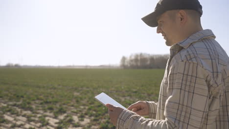 caucasian man in plaid shirt using a tablet and looking around in the countryside