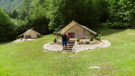 aerial view of couple standing in front of sitting area at a camping site.