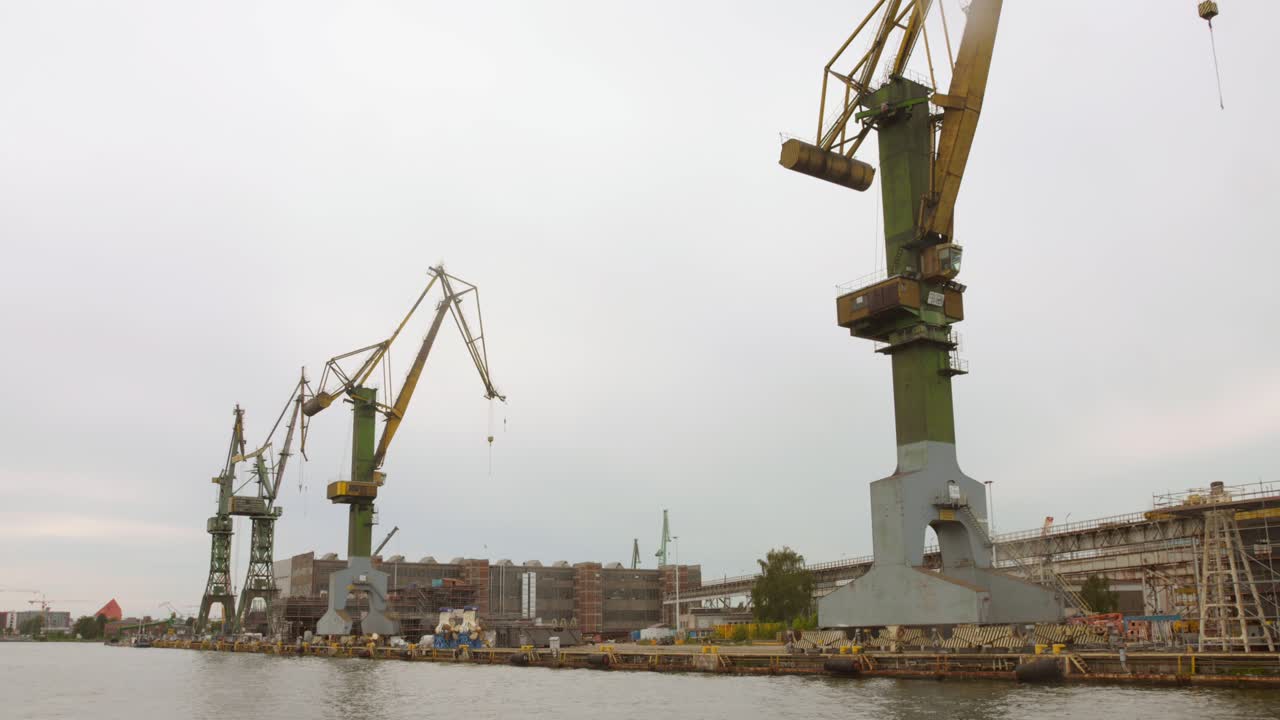 The harbor in Gdansk showcases its industrial might with towering cranes working efficiently on the waterfront. A bustling area with ongoing maritime activities.