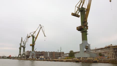 the harbor in gdansk showcases its industrial might with towering cranes working efficiently on the waterfront. a bustling area with ongoing maritime activities.