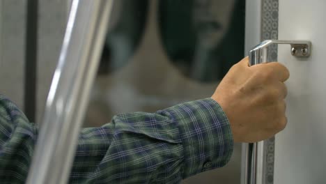 man holding hand rail on train