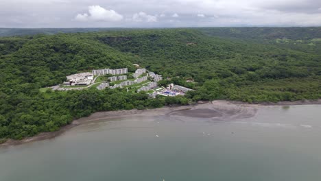 Aerial-pan-left-of-Planet-Hollywood-luxurious-hotel-near-sea-surrounded-by-woods-in-Nacascolo-beach,-Papagayo-Peninsula,-Costa-Rica