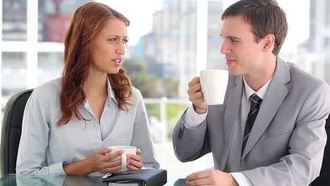 Two-colleagues-chatting-while-drinking-coffee