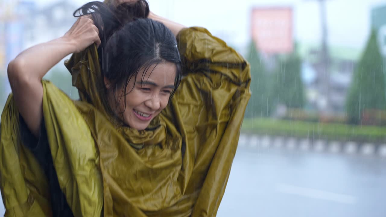 노란색 은 레인코트를 입은 쾌활한 아시아 여성의 초상화, 폭우 속에서 뛰어내리고, 비가 오는 날에 아지는 재미, 웃는 춤, 팔을 내밀고, 직원이 정서적 스트레스를 해소합니다.