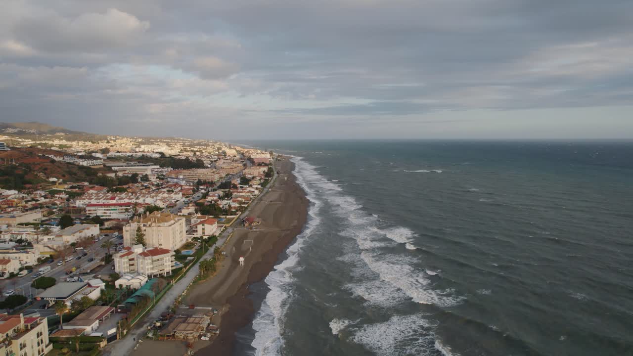 Costa y edificios en la playa de Málaga con las olas rompiendo en la orilla