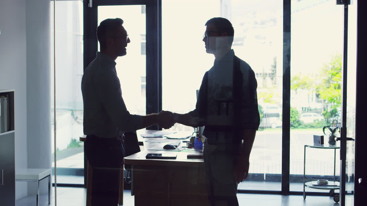 two businessmen shaking hands while standing