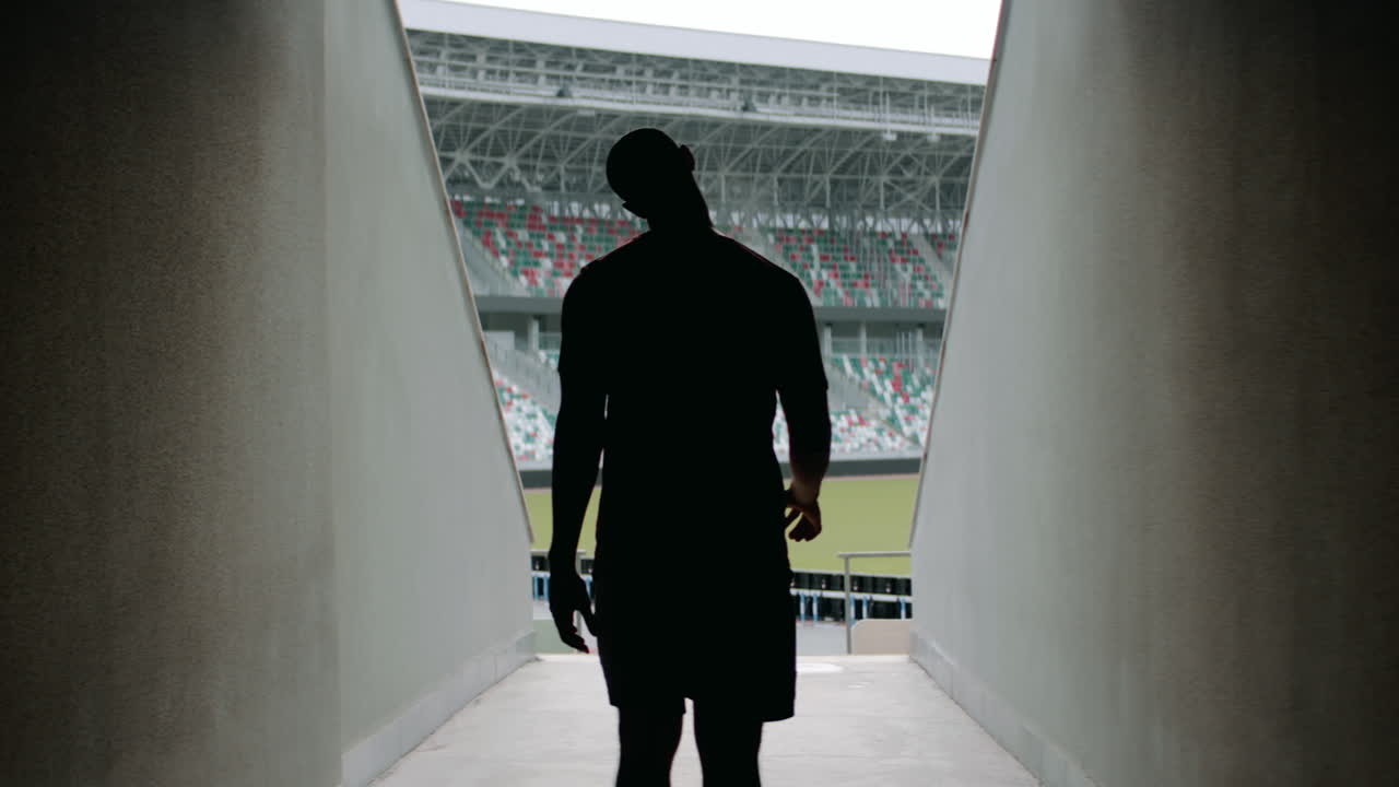 아프리카계 미국인 흑인 남성 선수가 아침 훈련 전에 경기장에 들어갑니다. 아나모르픽 렌즈로 촬영되었습니다.