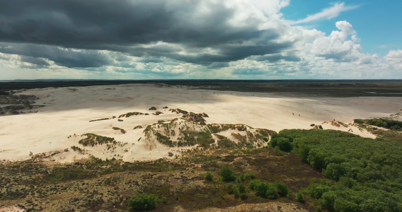 Droneoptagelse der afslører det vidtstrakte Råbjerg Mile landskab under dramatiske himmelstrøg.