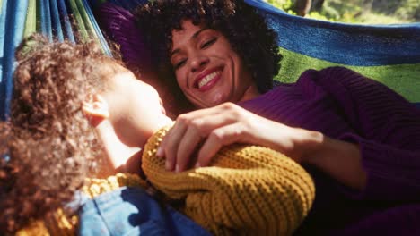 mother and daughter playing on a hammock in the woods