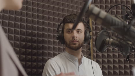 young man in a radio recording studio listens to the arguments of the female interlocutor next to him