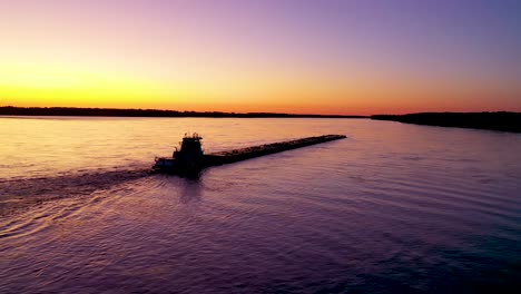 very good aerial of a tugboat pushing a barge up the mississippi river near memphis tennessee at sunset or dusk