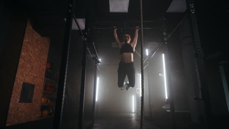 athletic woman is doing pull-up on crossbar in gym slow motion shot of swaying female body