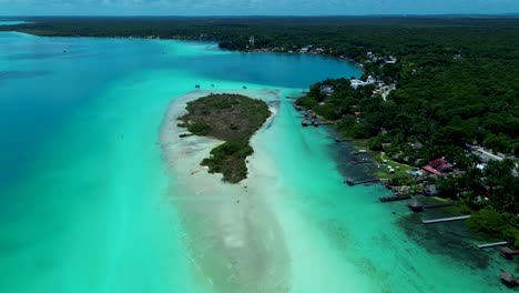 drone aerial landscape of crystal clear lagoon lake with sandbar island with cenote in bacalar suburbs rainforest village town mexico travel tourism holidays