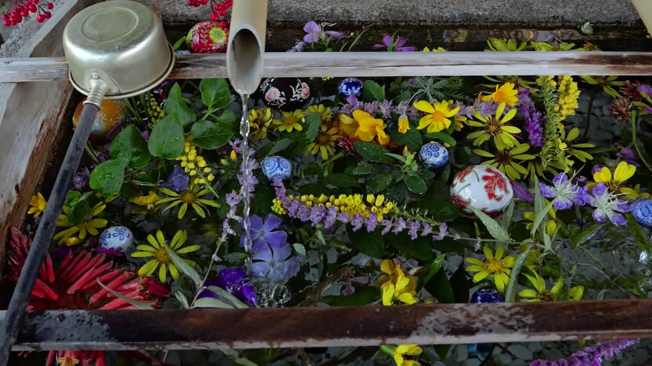 Filmatisk visning av en typisk japansk Chozu vannøse ved et tempel med fargerike blomster