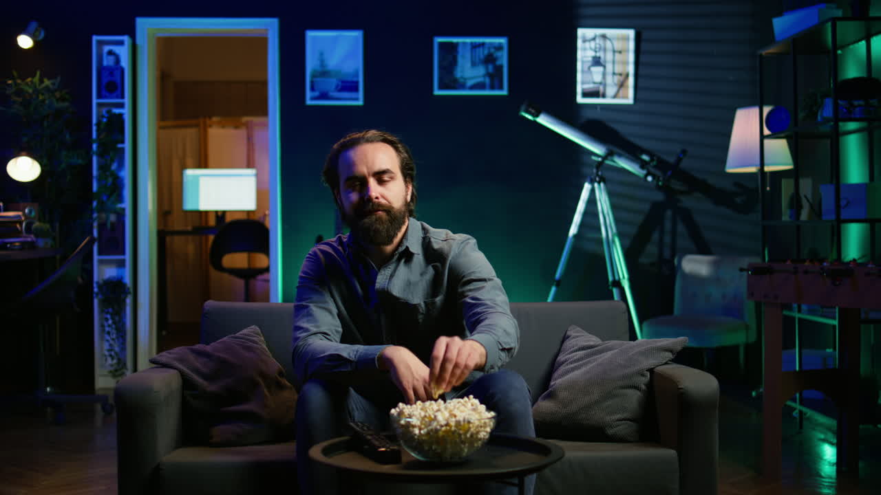 persona comiendo bocadillos y transmitiendo programas de televisión en la sala de estar iluminada con neón