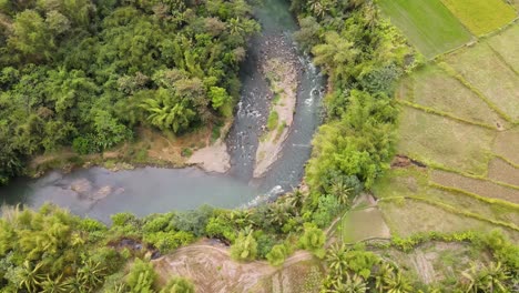 orbit drone shot of exotic winding rocky river flows through tropical country