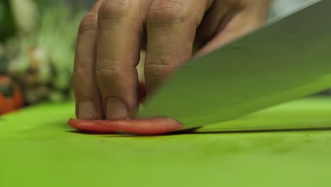 close up chef cutting tomato with sharp damascus steel knife