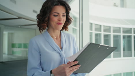 smiling boss reviewing documents on clipboard walking modern office closeup