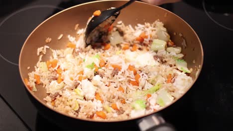 stirring and frying rice with vegetables in a pan