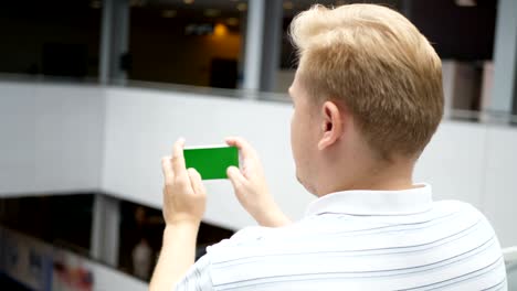 joven adolescente jugando a juegos en su teléfono inteligente en un café. joven hombre feliz jugando juegos en su smartphone. el teléfono inteligente se enciende en fondo blanco. pantalla verde fácil de personalizar. imagen generada por computadora.