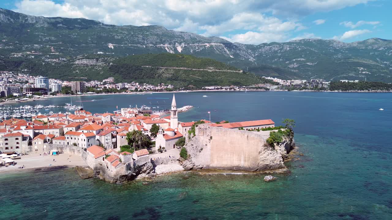 Citadel Budva, stone houses in old town on Adriatic coastline with mountains in backdrop, drone shot