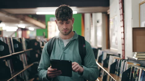 young man using tablet in a bookstore