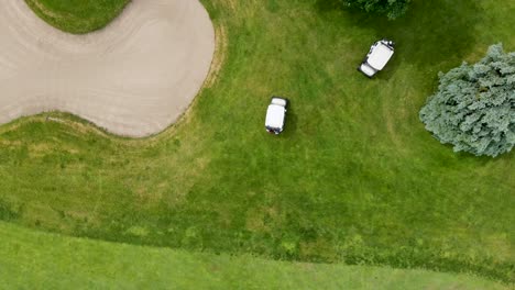 Top-down-aerial-view-of-golf-carts-driving-on-a-golf-course