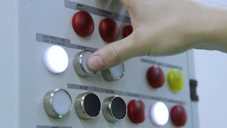 Human-hand-pressing-start-and-open-buttons-on-control-panel-at-factory