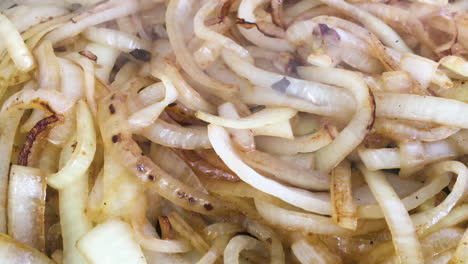 close up shot of some burger van style onions being fried on a griddle or grill