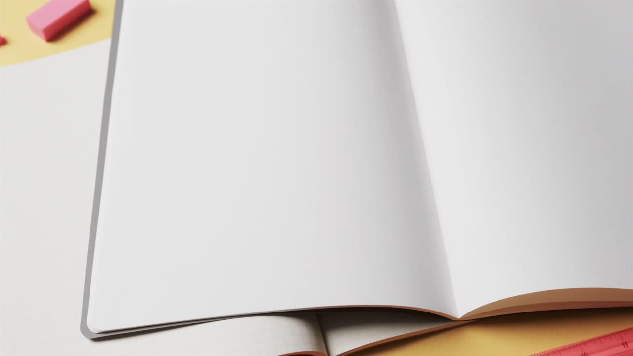 Close up of open notebooks with school stationery on beige background, in slow motion
