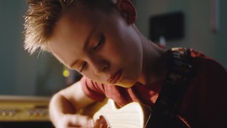 Focused Teen Musician Playing Guitar Concentrated Teenager Playing Electric Guitar and Controlling Sound Volume on Amplifier during Rehearsal at Home in Daytime