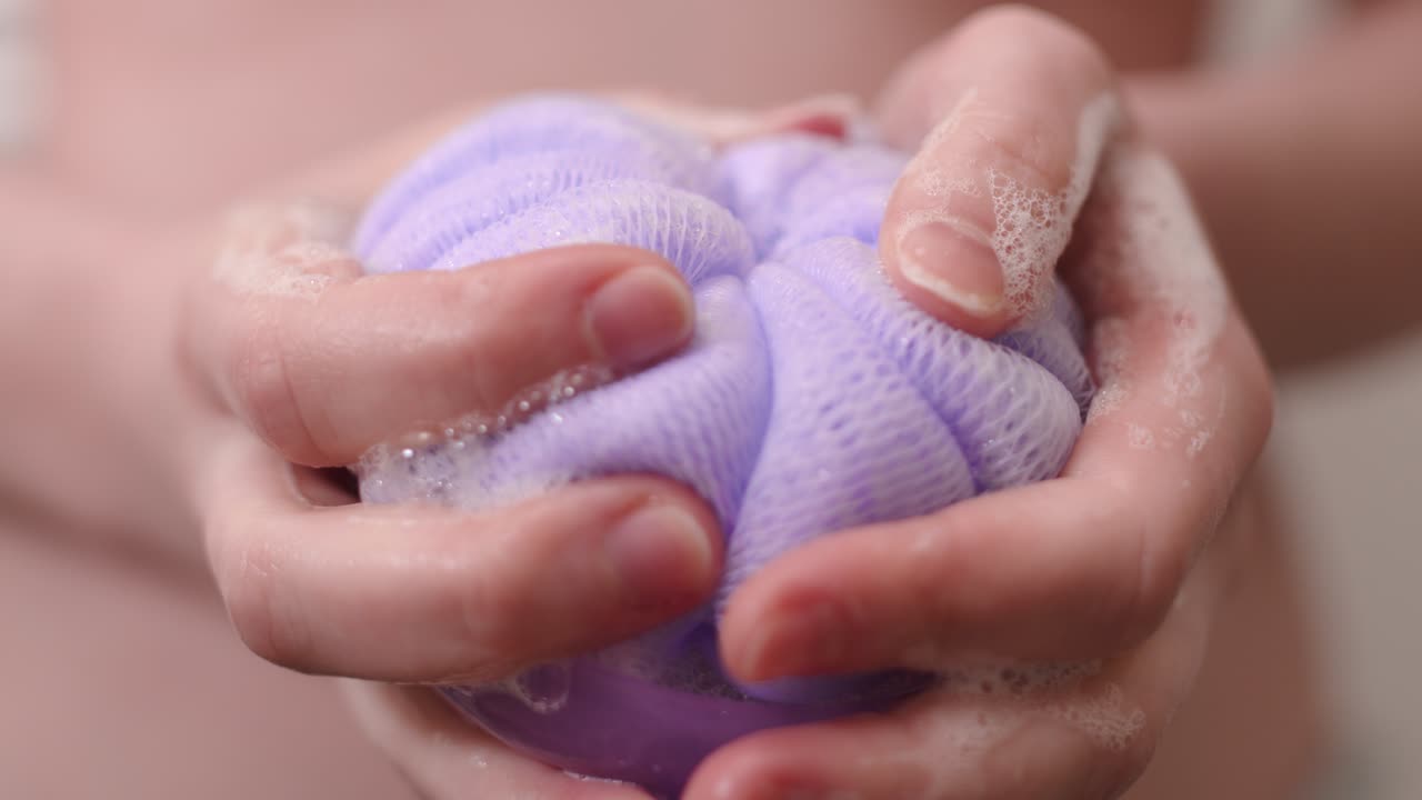 Foamy mesh bath sponge hold by pretty woman, close up view