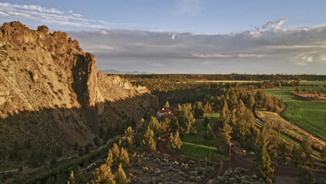 Terrebonne-Oregon-Aerial-V56-Fliegt-Um-Ein-Herrenhaus-An-Einer-Klippe-Mit-Blick-Auf-Den-Smith-Rock-State-Park-Mit-Einem-Krummen-Fluss,-Der-Sich-Bei-Sonnenuntergang-Durch-Die-Felsformationen-Schlängelt-–-Aufgenommen-Mit-Mavic-3-Cine-–-August-2022