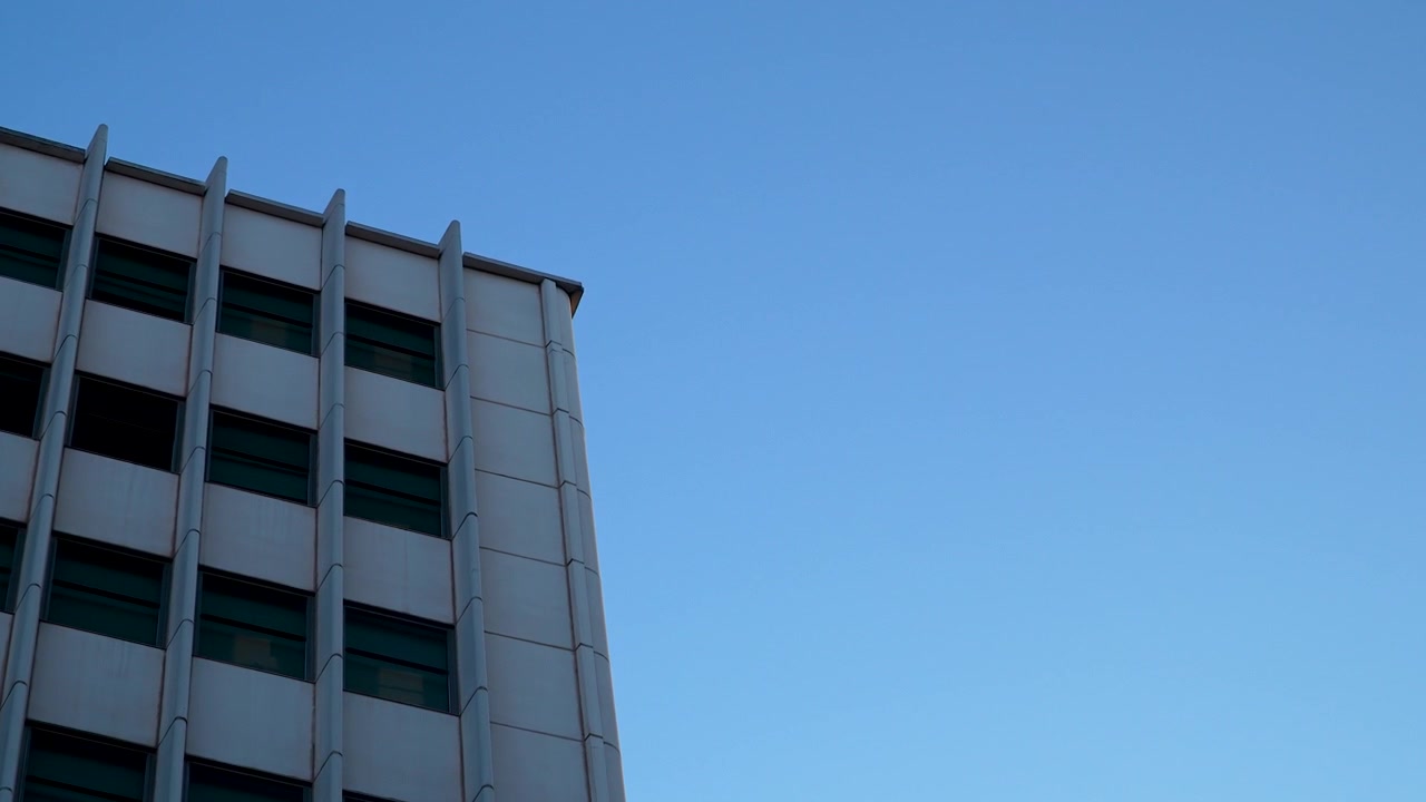 Plano de baixo ângulo do exterior de um edifício corporativo minimalista em Madrid, Espanha. Adequado para temas de negócios, arquitetura e desenvolvimento urbano.