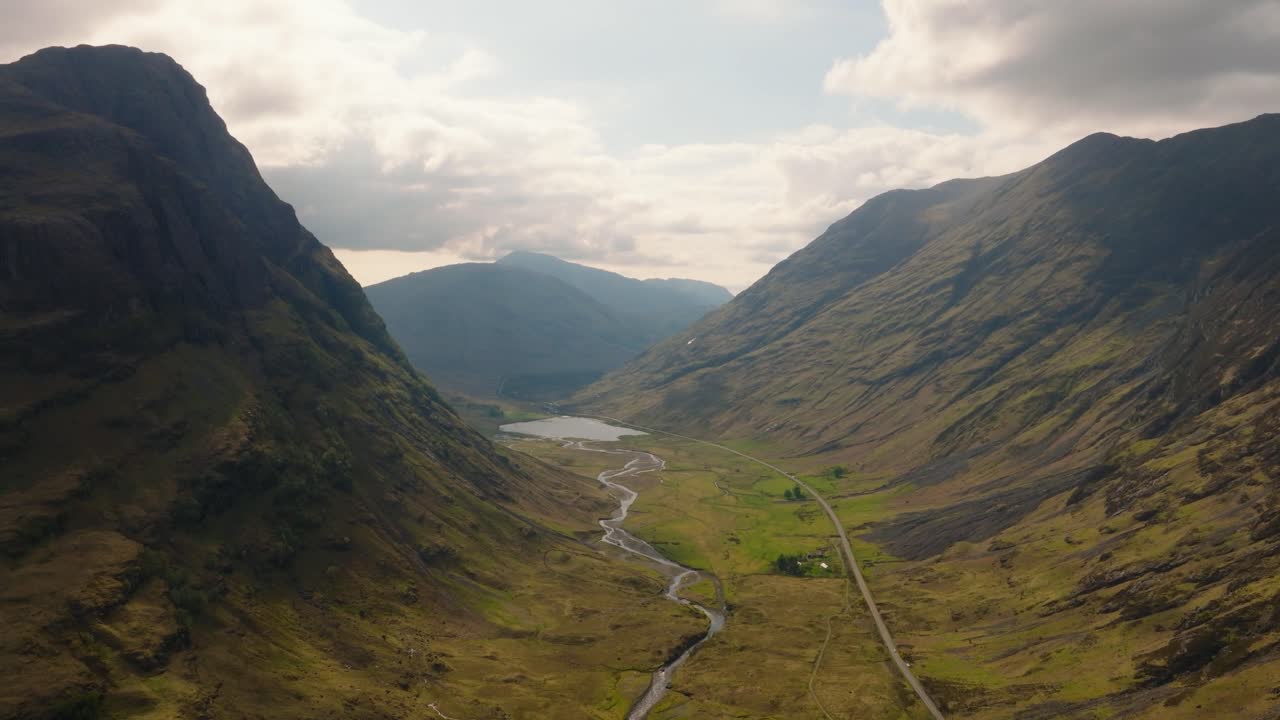 Imágenes aéreas de dron del espectacular valle de Glencoe en las Tierras Altas escocesas, capturadas con una luz tenue de antes del anochecer. Vistas panorámicas de montañas escarpadas, carreteras sinuosas y naturaleza salvaje e intacta.