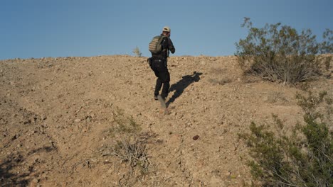 united states marines | special forces soldier in combat | walking forward with weapons ready | tactically walking through desert up a hill | middle eastern desert | 1 of 3