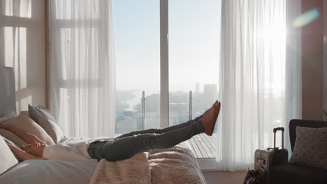 happy-young-woman-jumping-on-bed-resting-after-successful-travel-journey-enjoying-independent-lifestyle-freedom-in-hotel-room