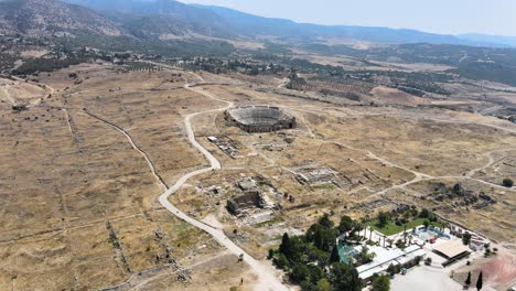 drone flight over a hotel with a swimming pool over the ruins of an ancient fortress over a mountain road against a background of mountains and blue sky